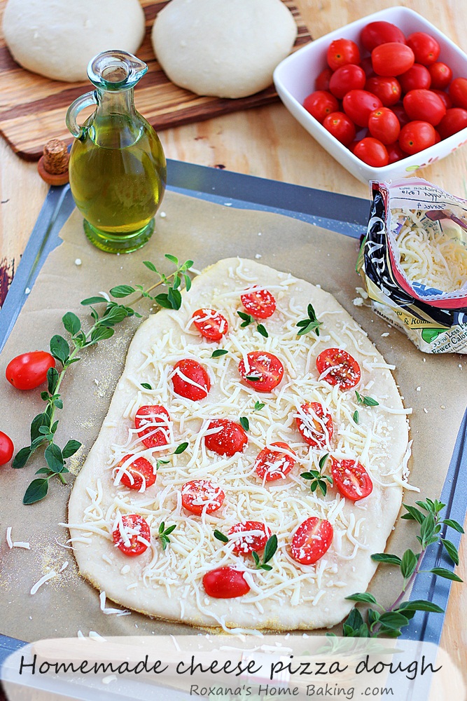 Made-from-scratch flavorful cheese pizza dough topped with more cheese and half graped tomatoes. Friday night pizza just got a whole lot better! Recipe from Roxanashomebaking.com